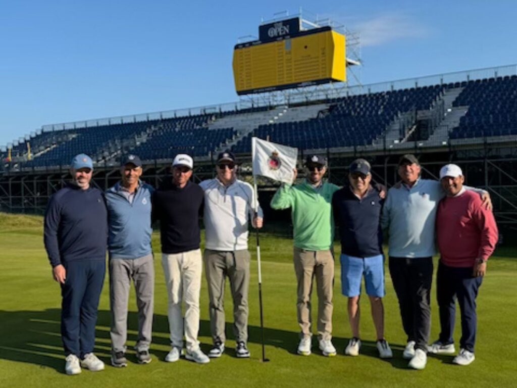 Justin Foster, PGA with his Ridgewood Country Club members under The Open scoreboard at Royal Portrush.
